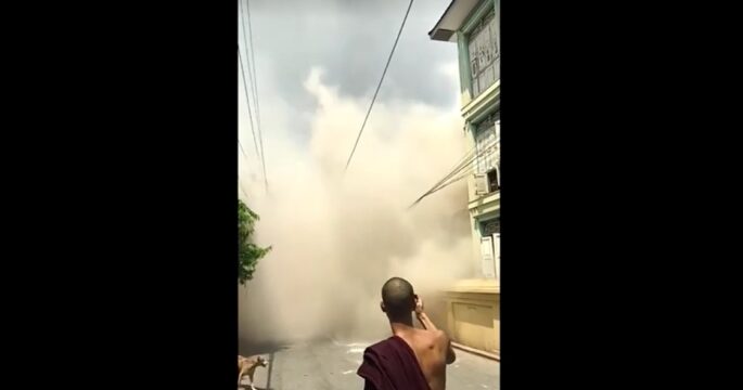 Building after collapses in Myanmar in front of monk's eye