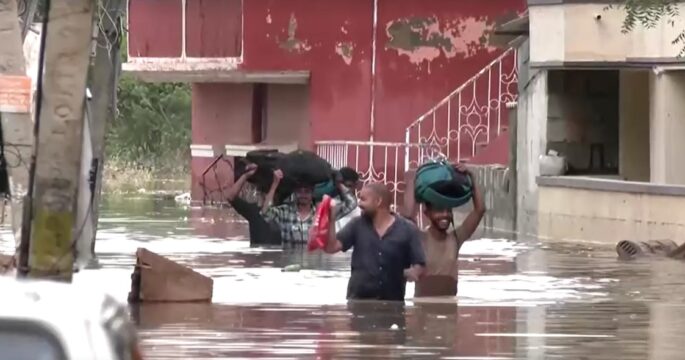 people wade through waist high flood in India