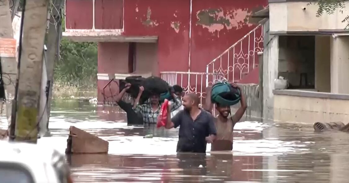 people wade through waist high flood in India